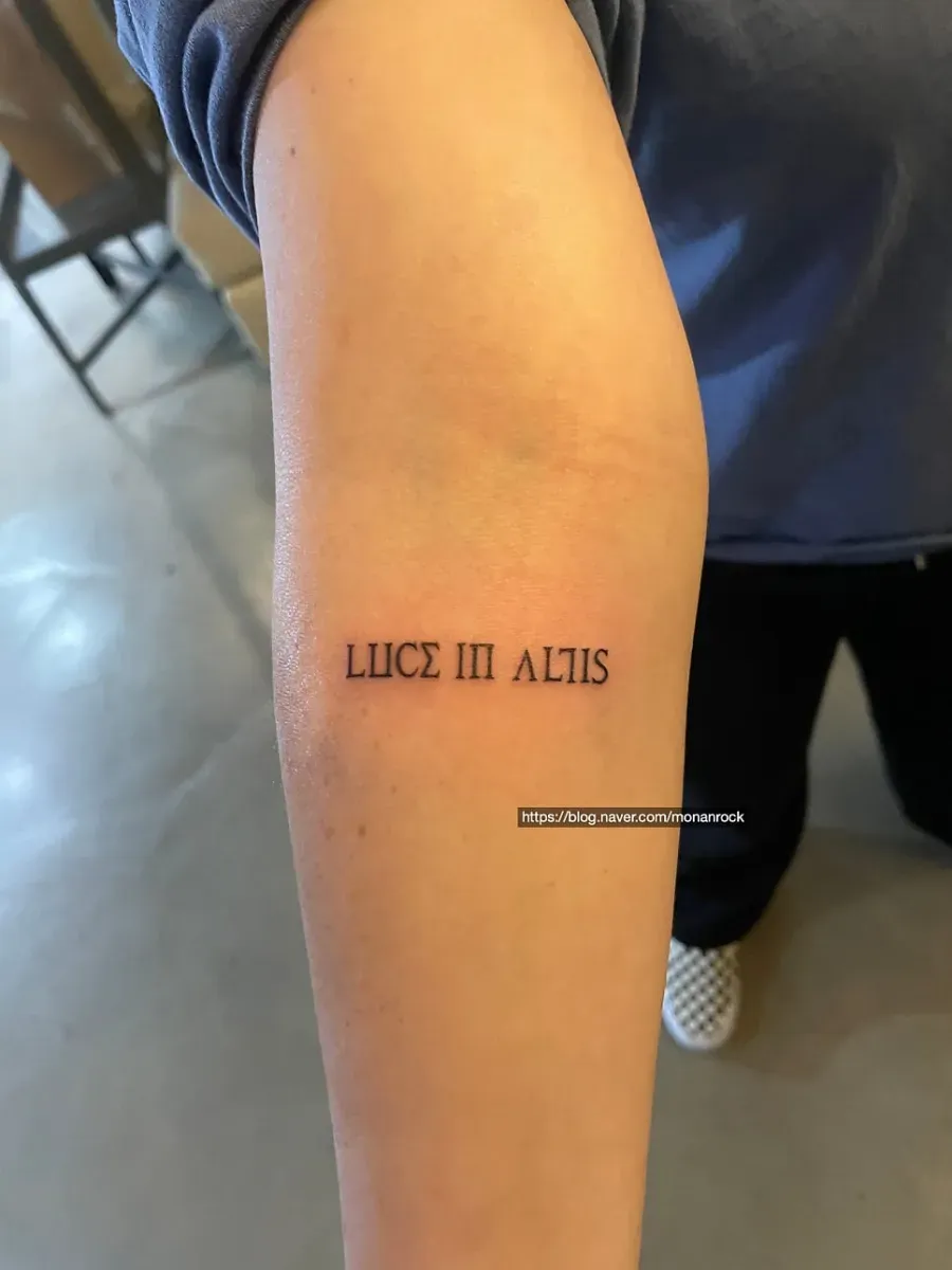 빛을 향한 메시지, 팔에 새긴 Luce in altis 레터링 타투 - 1